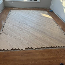 Carpet was removed from the center of the dining room. The space was then filled in on a 45 with a walnut / maple border and a walnut, oak and maple inlay. Oak was stained with Latte Macchiato with a satin finish on top.