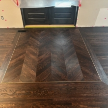 Red Oak flooring laid in a chevron pattern with a border and brass inlay.  An antique gold top step vent was also cut in to finish the look.  Floor was finished with Berger Seidle Base Oil in Ebony