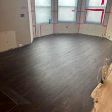 Red Oak flooring laid in a chevron pattern with a border and brass inlay.  An antique gold top step vent was also cut in to finish the look.  Floor was finished with Berger Seidle Base Oil in Ebony