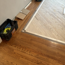 Carpet was removed from the center of the dining room. The space was then filled in on a 45 with a walnut / maple border and a walnut, oak and maple inlay. Oak was stained with Latte Macchiato with a satin finish on top.