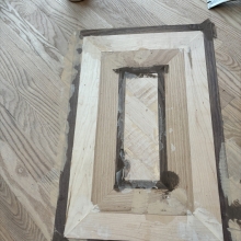 Carpet was removed from the center of the dining room. The space was then filled in on a 45 with a walnut / maple border and a walnut, oak and maple inlay. Oak was stained with Latte Macchiato with a satin finish on top.